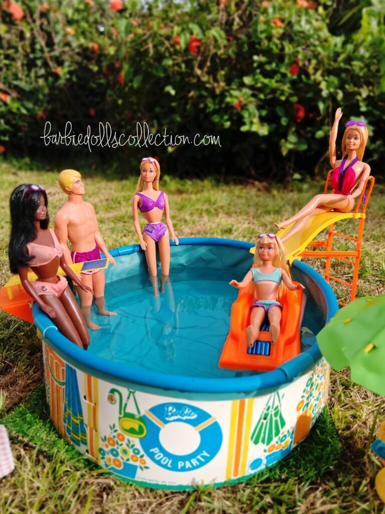 Malibu Barbie and her friends enjoying a summer pool party, with Barbie on the waterslide, Skipper relaxing on a pool float, and Ken, PJ, and Christie standing in the water.