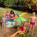 Malibu Barbie, Ken, Skipper, PJ, and Christie posing together by the swimming pool and looking at the camera during a vintage summer Barbie pool party diorama.