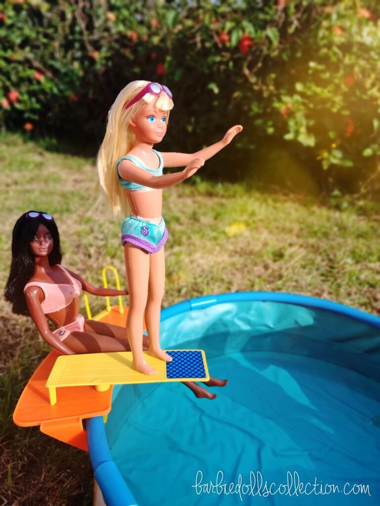 Skipper standing on the diving board ready to jump into the pool while Christie watches during the vintage Barbie summer pool party diorama.
